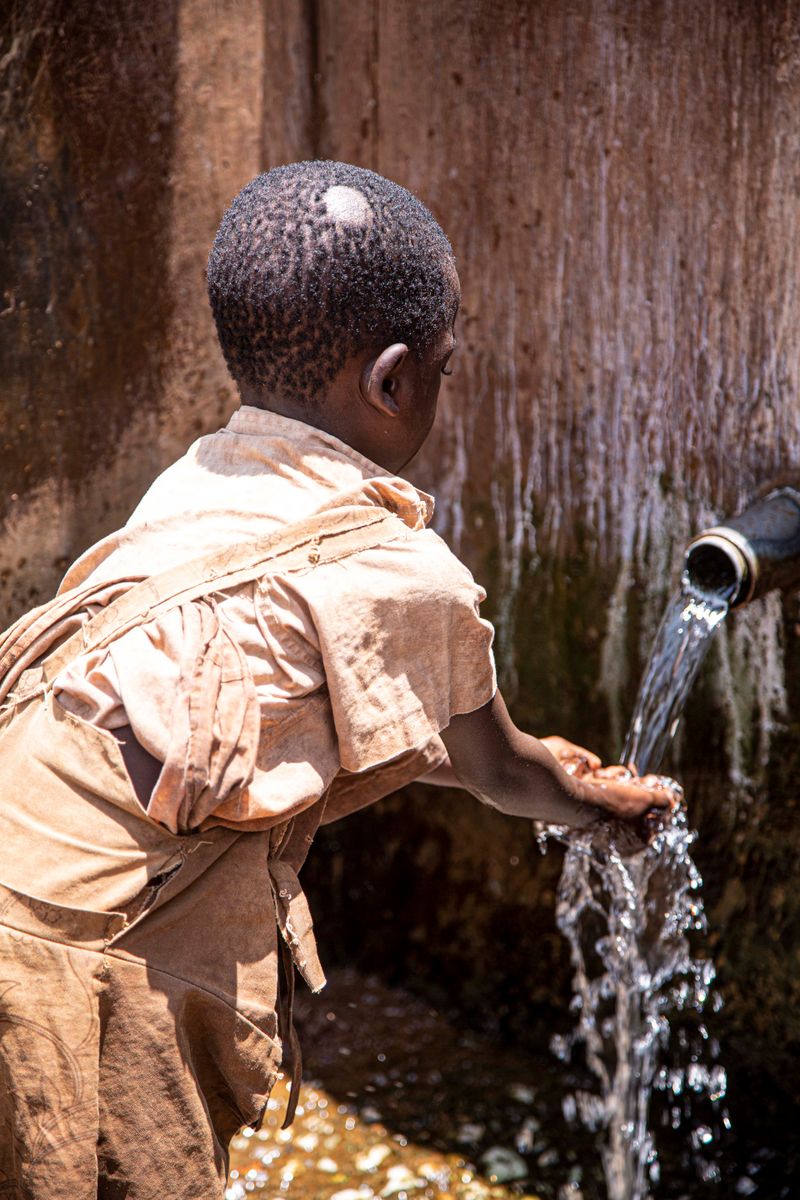 A child gathers clean water from an outdoor tap
