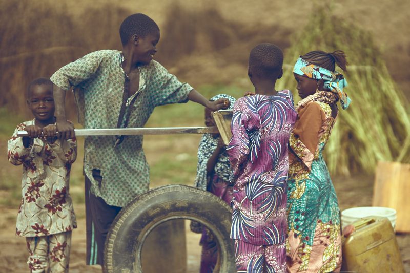 Children gather around a water pump